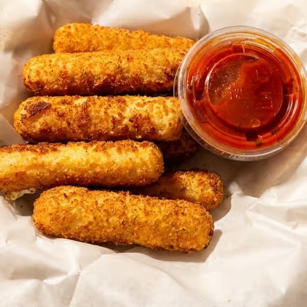 Golden-brown breaded mozzarella sticks served with a cup of red marinara dipping sauce.
